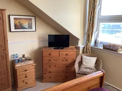 a living room with a tv on a dresser and a chair at Struan House B&B in Tarbert