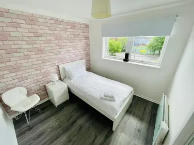 a small bedroom with a bed and a brick wall at Modern 2 bedroom Apartment Near City Centre in Glasgow