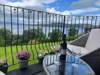 a table with wine glasses on a balcony with a view at Loch View at Lomond Castle in Balloch