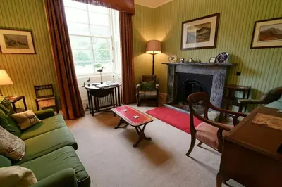 a living room with a green couch and a fireplace at Chesthill House and Estate, Glen Lyon in Aberfeldy