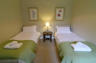 two twin beds in a room with a lamp at Chesthill House and Estate, Glen Lyon in Aberfeldy