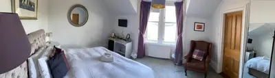 a bedroom with a bed and a chair and a window at The Colintraive in Colintraive