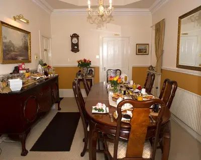 a dining room with a wooden table and chairs at Craig Park House in Airdrie