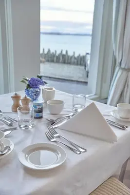 a table with white plates and silver utensils on it at Crinan Hotel in Crinan