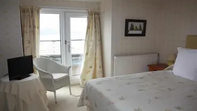 a bedroom with a bed and a tv and a window at Crinan Hotel in Crinan