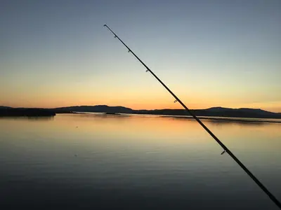 a view of a lake at sunset with a fishing rod at Tidereach - Otters View in Connel