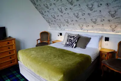 a bedroom with a bed with a green blanket at Lochnell Arms Hotel in Oban