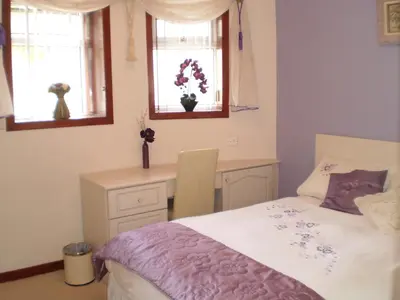 a bedroom with a bed and a desk and windows at Shawlee Cottage in Airdrie