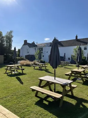 a group of picnic tables with an umbrella on top at The Smiddy Haugh in Auchterarder