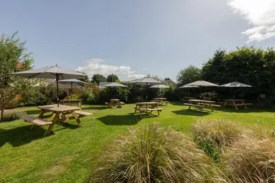 a group of picnic tables and umbrellas in a field at The Smiddy Haugh in Auchterarder