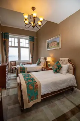 a bedroom with two beds and a chandelier at The Glenburn Hotel in Rothesay