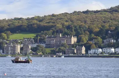 a boat in the water in front of a town at The Glenburn Hotel in Rothesay