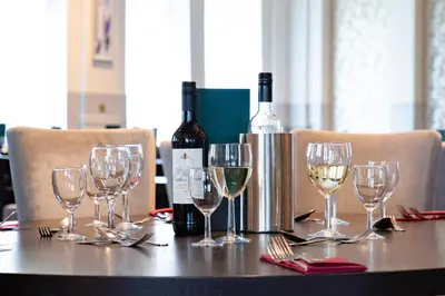 a table with wine bottles and wine glasses on it at The Great Western Hotel in Oban