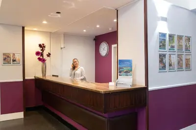 a woman talking on a cell phone at a reception desk at The Great Western Hotel in Oban