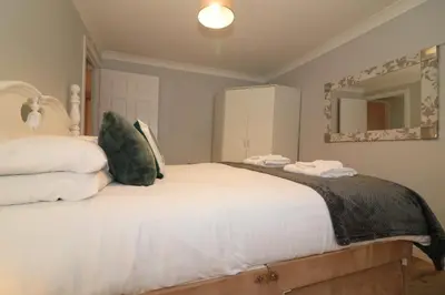 a bedroom with a large white bed with a mirror at Signature - Stanfield House in Motherwell