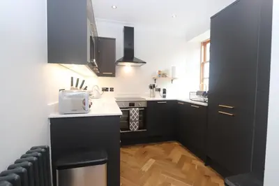 a kitchen with black cabinets and a white counter top at Charming two bedroom, two bathroom detached cottage in Boʼness