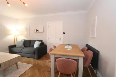 a living room with a table and a couch at Charming two bedroom, two bathroom detached cottage in Boʼness