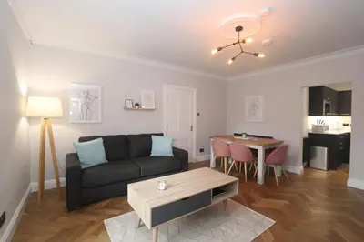 a living room with a couch and a table at Charming two bedroom, two bathroom detached cottage in Boʼness