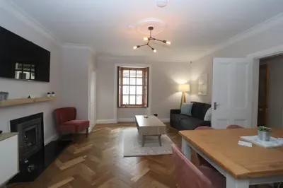 a living room with a dining table and a living room with a fireplace at Charming two bedroom, two bathroom detached cottage in Boʼness