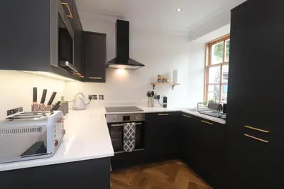 a kitchen with black cabinets and white counter tops at Charming two bedroom, two bathroom detached cottage in Boʼness