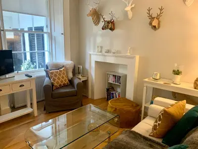 a living room with a couch and a chair and a fireplace at Stylish City Centre Apartment in Edinburgh