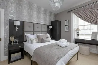 a bedroom with a large white bed and a chandelier at Elegant Flat Near Princes Street - Perfect Location, 24-7 Customer Support in Edinburgh