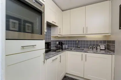 a kitchen with white cabinets and a sink at Elegant Flat Near Princes Street - Perfect Location, 24-7 Customer Support in Edinburgh