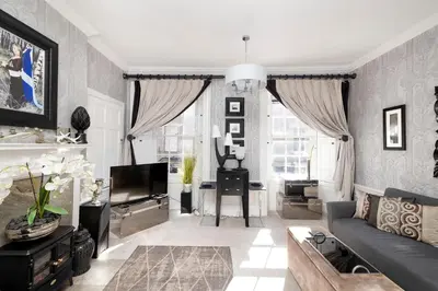a living room with a couch and a tv at Elegant Flat Near Princes Street - Perfect Location, 24-7 Customer Support in Edinburgh