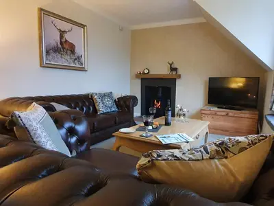 a living room with leather furniture and a fireplace at Ben Ledi View in Callander