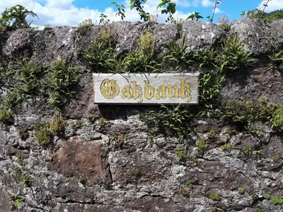 a sign on the side of a rock wall at Ben Ledi View in Callander