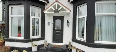 a white house with a black door and windows at Montague Villa in Dunoon