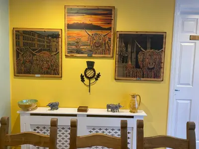 a dining room with a table and paintings on the wall at Montague Villa in Dunoon