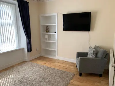 a living room with a tv and a chair at 105 Nelson Street in Largs