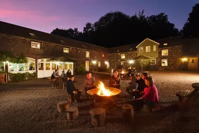 a group of people sitting around a fire at night at Comrie Croft in Crieff