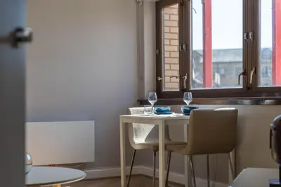 a table with two glasses and two chairs next to a window at Stunning 1 Bed Merchant City Apartment with Parking in Glasgow