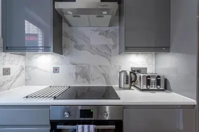 a kitchen with a sink and a stove top oven at Stunning 1 Bed Merchant City Apartment with Parking in Glasgow