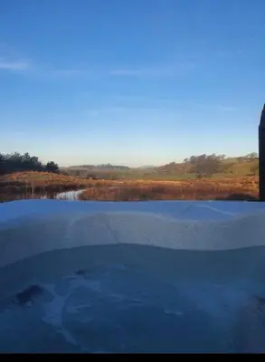 a reflection of a pool of water in a field at Pond View Pod 1 with Outdoor Hot Tub - Fife - Loch Leven - Lomond Hills in Kelty
