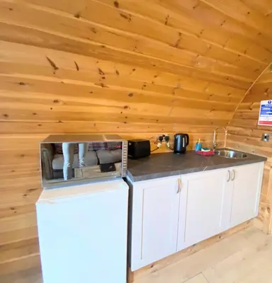 a kitchen with a refrigerator and a sink in a cabin at Pond View Pod 1 with Outdoor Hot Tub - Fife - Loch Leven - Lomond Hills in Kelty