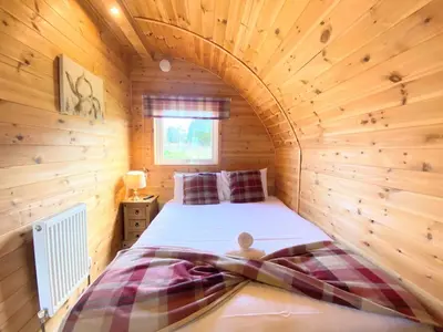 a bedroom with a bed in a wooden room at Pond View Pod 1 with Outdoor Hot Tub - Fife - Loch Leven - Lomond Hills in Kelty