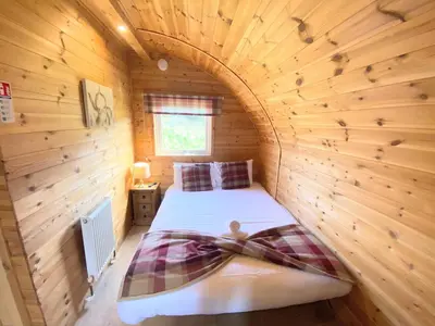 a bedroom with a bed in a wooden room at Pond View Pod 1 with Outdoor Hot Tub - Fife - Loch Leven - Lomond Hills in Kelty