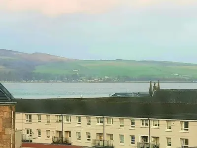 a large white building with a large body of water at Glen View Apartments in Port Glasgow