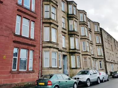 two cars parked in front of a brick building at Glen View Apartments in Port Glasgow