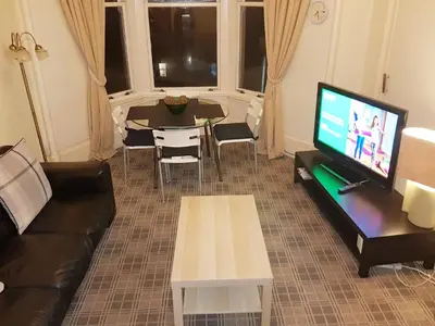 a living room with a couch and a tv and a table at Glen View Apartments in Port Glasgow