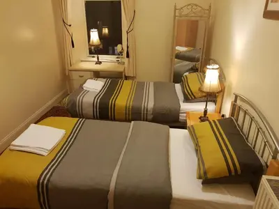 a hotel room with two beds and a mirror at Glen View Apartments in Port Glasgow
