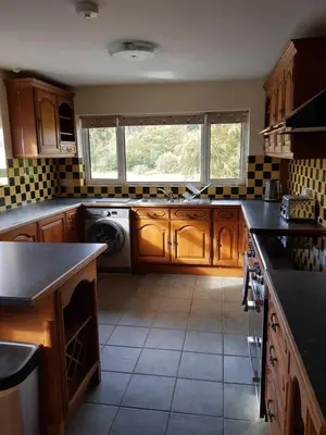 a kitchen with wooden cabinets and a washer and dryer at Cleughfoot House in Moffat