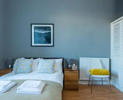 a blue bedroom with a bed and a chair at The Westfield in Edinburgh