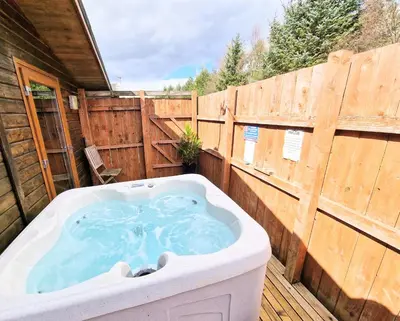 a hot tub on a deck with a wooden fence at Ochil 8 with Private Hot Tub - Fife - Loch Leven - Lomond Hills in Kelty