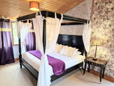a bedroom with a canopy bed with purple sheets at Ochil 8 with Private Hot Tub - Fife - Loch Leven - Lomond Hills in Kelty