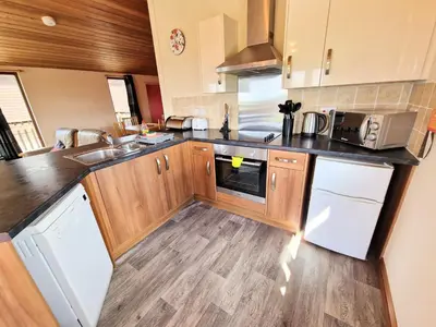 a kitchen with wooden cabinets and white appliances at Lomond 4 with Private Hot Tub - Fife - Loch Leven - Lomond Hills in Kelty