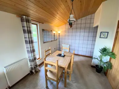 a dining room with a wooden table and chairs at Lomond 6 with Private Hot Tub - Fife - Loch Leven - Lomond Hills in Kelty